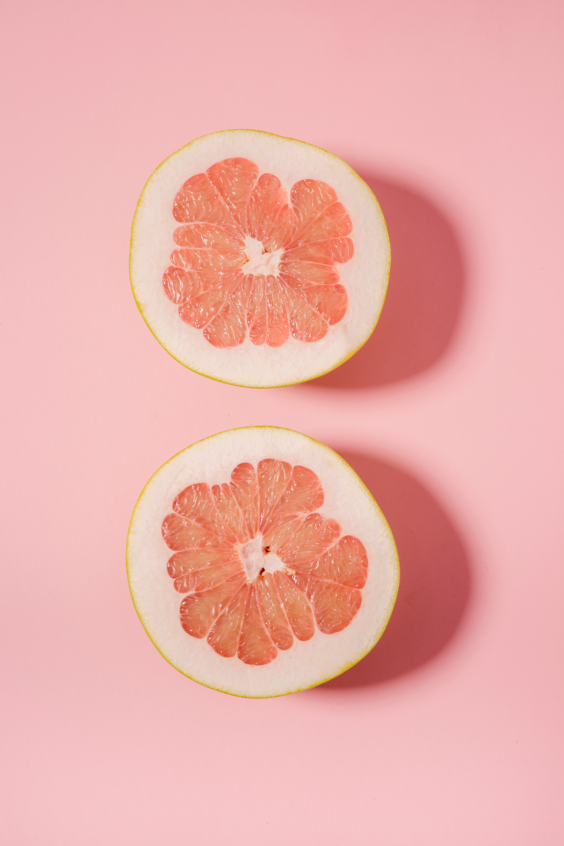 Sliced juicy grapefruit on pink surface